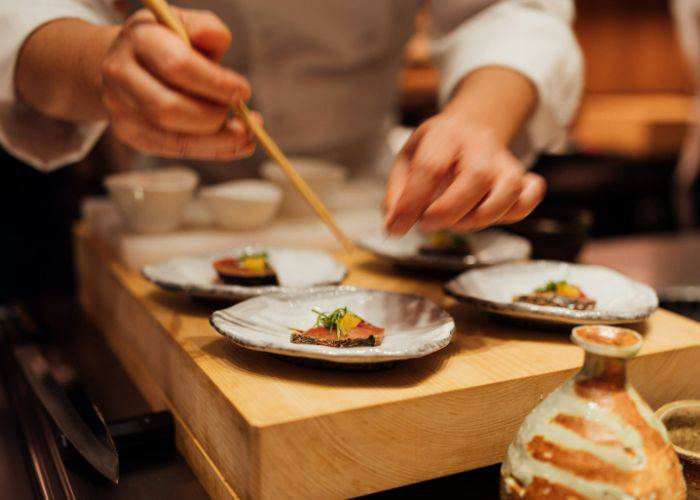 A chef serving up omakase sushi, adding the finishing touches to a sushi platter.